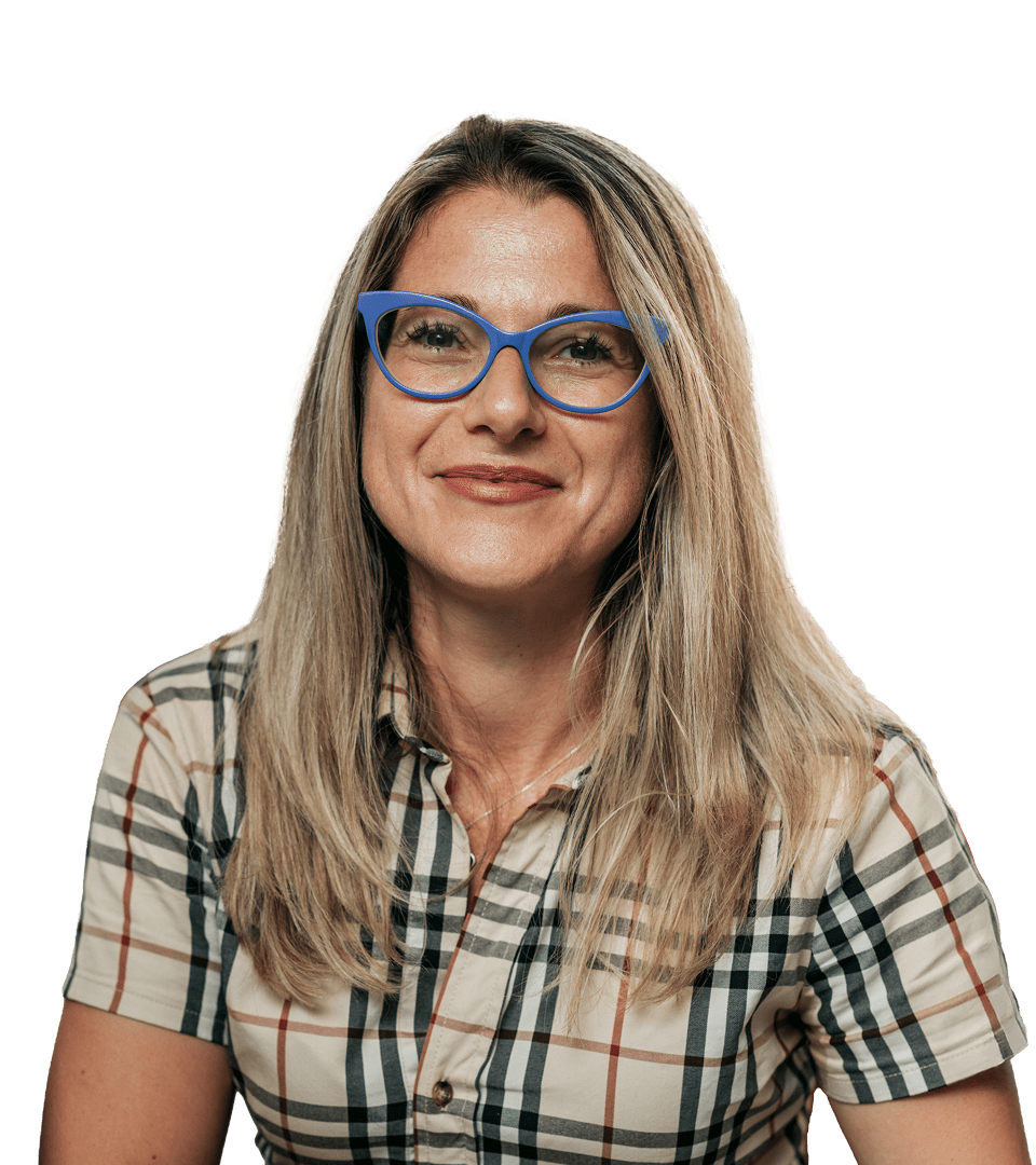 Portrait of a woman in the Genoa office with long blond hair and bright blue-framed glasses. He wears a plaid shirt in beige, black and red and looks smiling towards the camera